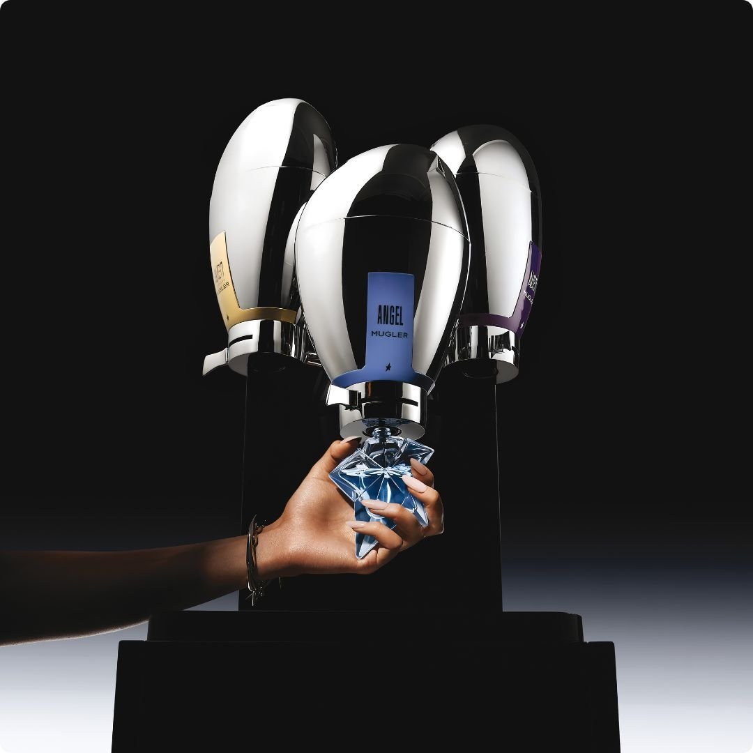 2026 loreal luxe brand mugler big silver bottles on black stand and a blue star bottle