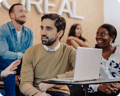 Mann sitzt vor seinem Laptop und unterhält sich, im Hintergrund das Loreal-Logo